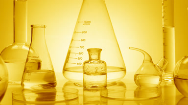 Drops drip in bottle surround by glassware on yellow background