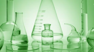 Drops drip in bottle surrounded by glassware on green background
