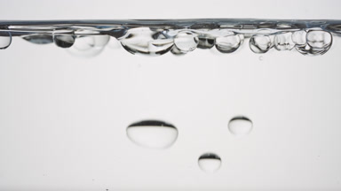 Bubbles float to the surface bouncing off it on grey background