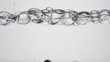 Transparent bubbles float to the surface on grey background