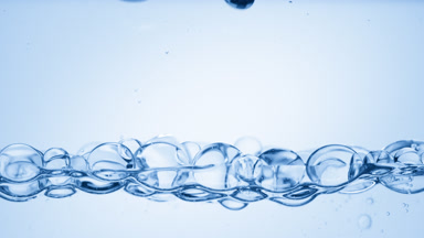 Transparent bubbles float to the surface on blue background
