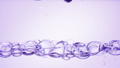 Transparent bubbles float to the surface on purple background