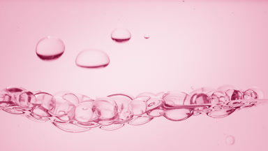 Transparent bubbles go down to the surface on pink background