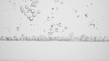 Small clear bubbles go down to the surface on grey background