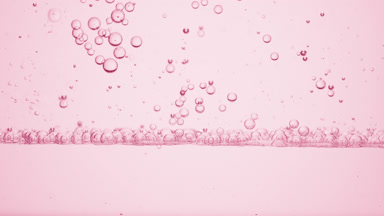 Small clear bubbles go down to the surface on pink background