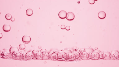 Bubbles of rose oil go down to another on pale pink background