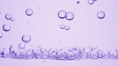 Bubbles of lavender oil go down to another on purple background