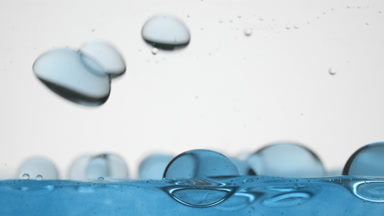 Blue bubbles fall to blue surface bouncing on grey background