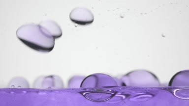 Purple bubbles fall to purple surface bouncing and bursting