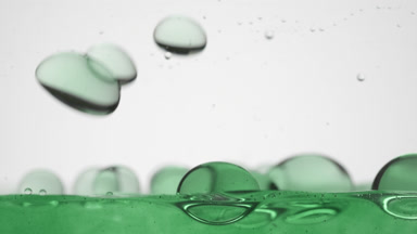 Green bubbles fall to green surface bouncing on grey background