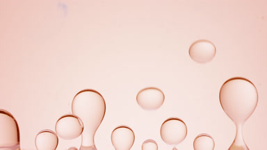 Beige transparent bubbles form and float on beige background