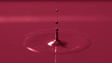 Red drop drips on red opaque liquid creating circles on it