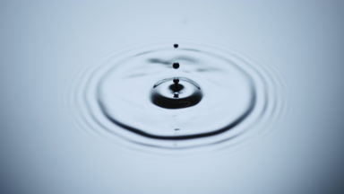 Black drop drips on black opaque fluid with light reflection