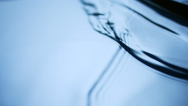 Macro of black brush creates ripples on dark-blue opaque liquid