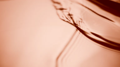 Macro of black brush creates ripples on beige opaque liquid