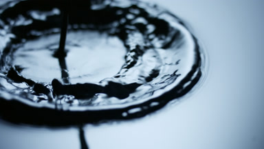 Black opaque liquid pours and drips on its surface splashing