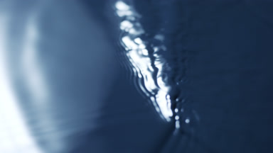 Rippling surface of dark-blue opaque fluid with light reflection