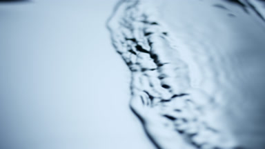 Side view of small waves on dark-blue opaque liquid surface