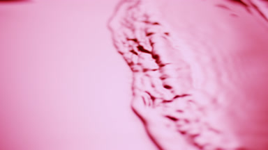 Side view of small waves on pink opaque liquid surface