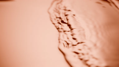 Side view of small waves on beige opaque liquid surface