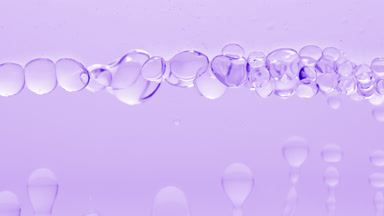 Clear bubbles form and float to another on violet liquid surface