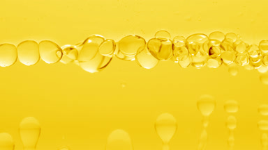 Clear bubbles form and float to another on yellow liquid surface