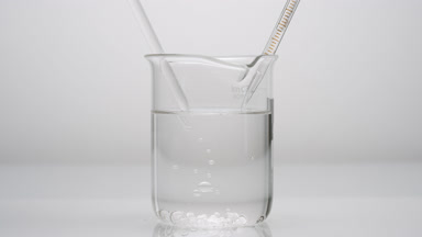 Dropper drips liquid which sink in beaker on grey background