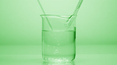 Dropper drips liquid which sink in beaker on green background