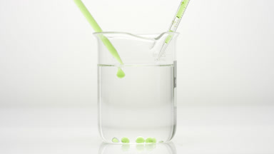 Dropper drips hemp oil into water in beaker which sink to bottom