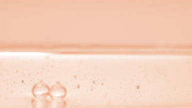 Beige bubbles sink to the liquid surface on beige background