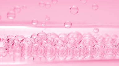 Pink transparent bubbles sink to fluid surface with another ones