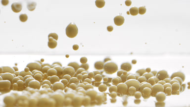 Yellow opaque bubbles sink to liquid surface with another ones