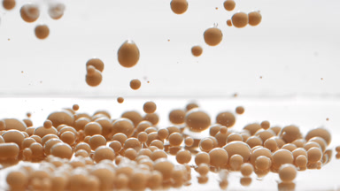 Beige opaque bubbles sink to liquid surface with another ones