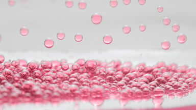 Pink transparent bubbles fall down to another on grey background