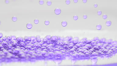 Purple transparent bubbles fall to another on grey background