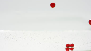 Red opaque bubbles sink to the liquid surface on grey background