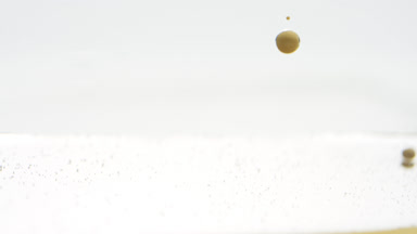 Yellow opaque bubbles sink to liquid surface on grey background