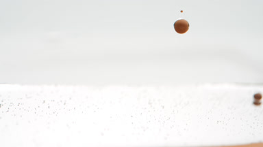 Orange opaque bubbles sink to fluid surface on grey background