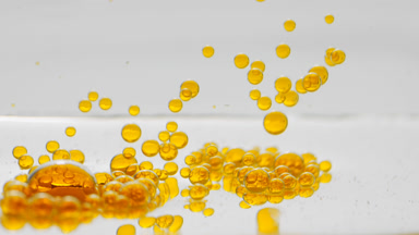 Yellow clear bubbles sink to liquid surface on grey background