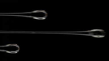 Macro of three flows of grey viscous liquid on black background