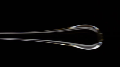 Macro of drop of grey viscous liquid flowing on black background