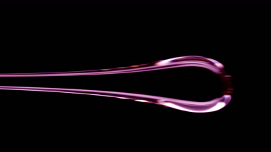 Drop of purple viscous liquid flowing on black background