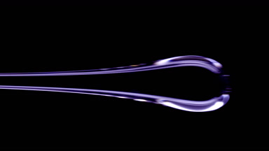 Drop of violet viscous liquid flowing on black background