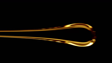 Macro of drop of yellow viscous liquid flowing on black background