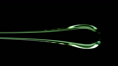 Drop of green viscous liquid flowing on black background