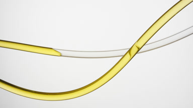 Yellow oil is filling lab connecting tube on grey background