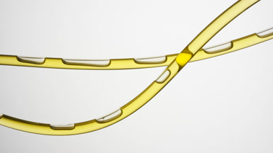 Yellow oil is flowing in two connecting tubes on grey background