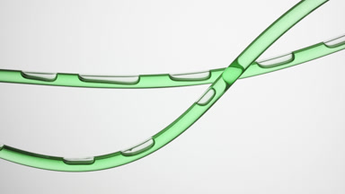 Green oil is flowing in two connecting tubes on grey background