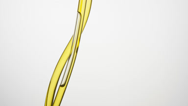 Jojoba oil flowing down in connecting tubes on grey background