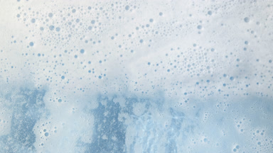 Water wave flows creating a lot of foam on blue background
